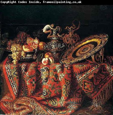 Jacques Hupin A still life of peaches, grapes and pomegranates in a pewter bowl, an ornate ormolu plate and ewers, all resting on a table draped with a carpet